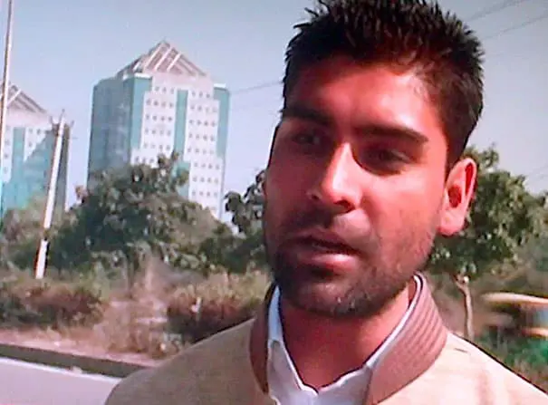 Close-up of a man outdoors with tall buildings in the background.