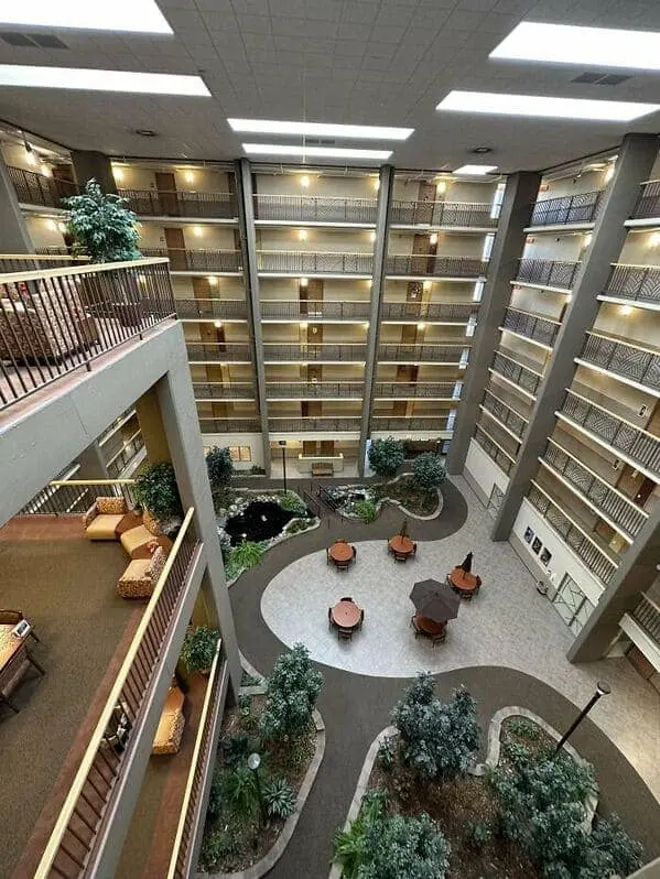 A creepy liminal space looking down into a massive, empty hotel atrium with many balconies.