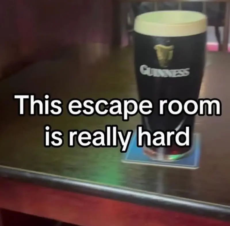 deadpan irish meme showcases a single pint of Guinness sitting on a dark wooden bar top with the ironic, dry caption: "This escape room is really hard."