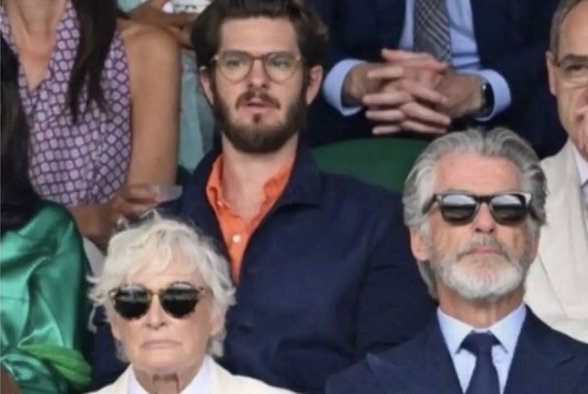 Andrew Garfield, Glenn Close, and Pierce Brosnan sitting together in a stadium crowd at Wimbledon.