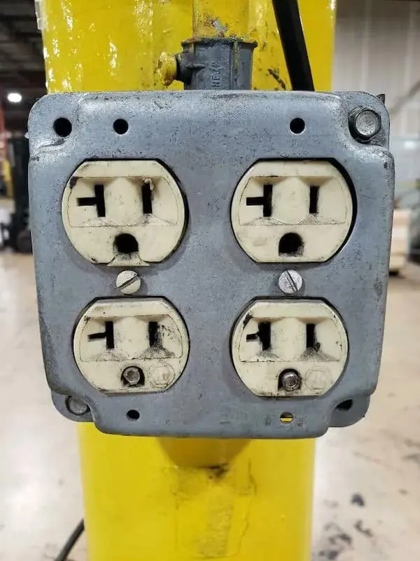 A frustrated funny picture of an industrial quad electrical outlet where both bottom sockets are rendered useless by snapped-off ground pins stuck inside them.