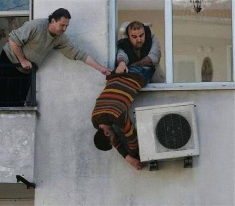 guys holding a guy upside down out a window