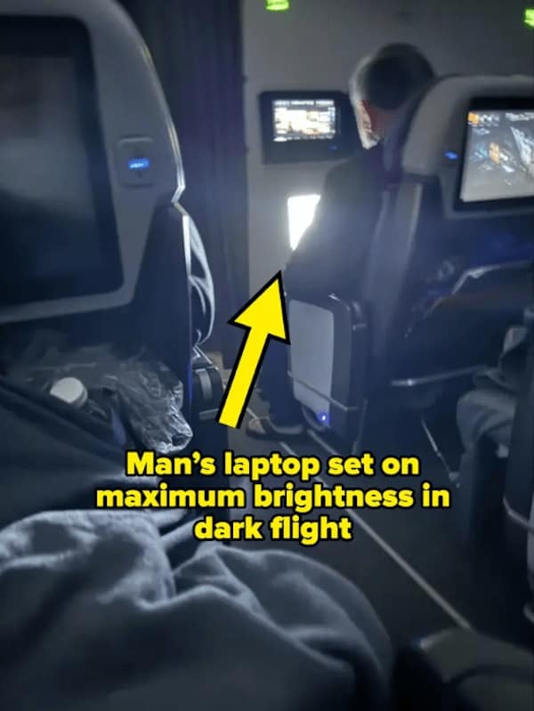 Man's laptop set on maximum brightness in dark flight