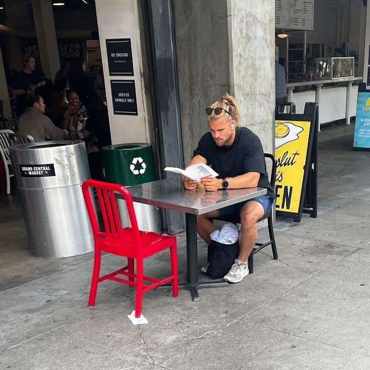Man reading a book alone at an outdoor cafe table