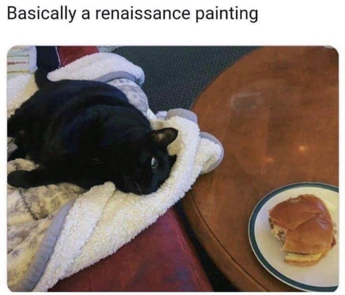 Black cat stares longingly at a sandwich while lying on a blanket