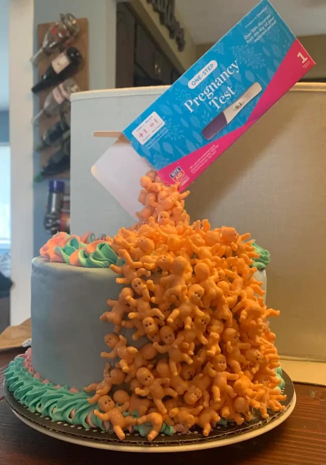A very cursed and funny cake for a baby shower featuring a pregnancy test and tiny babies.
