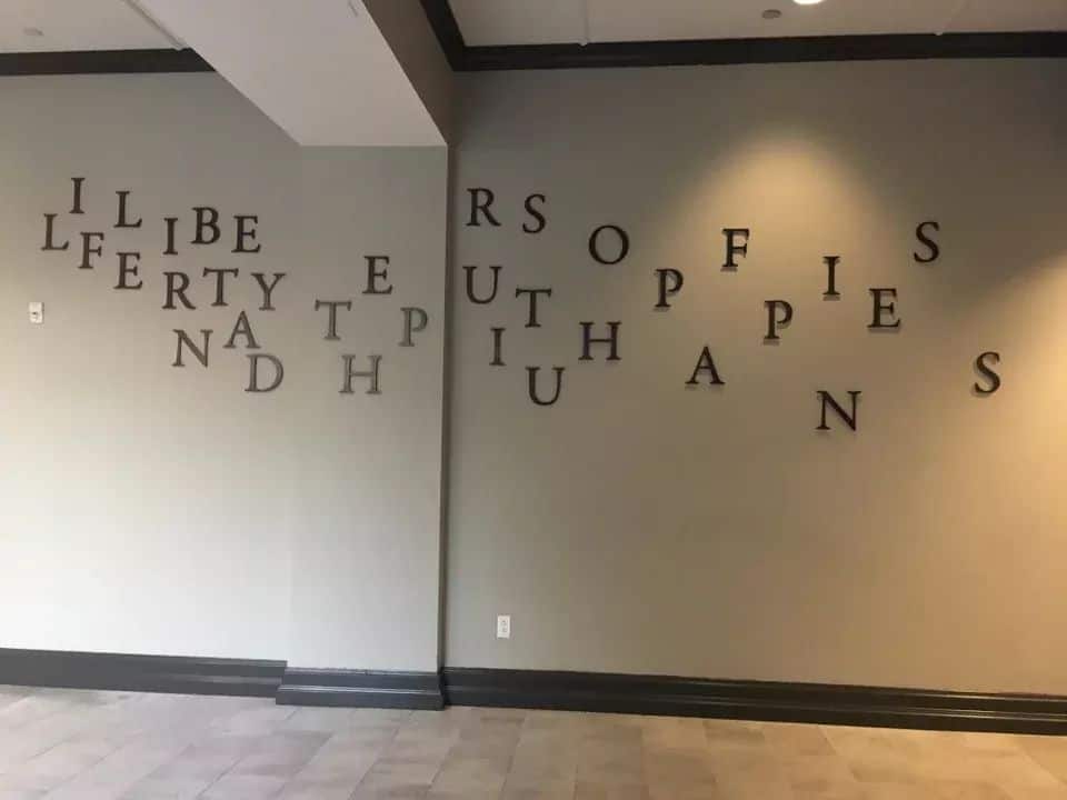 An office wall with jumbled letters scattered randomly, making the intended message completely unreadable.