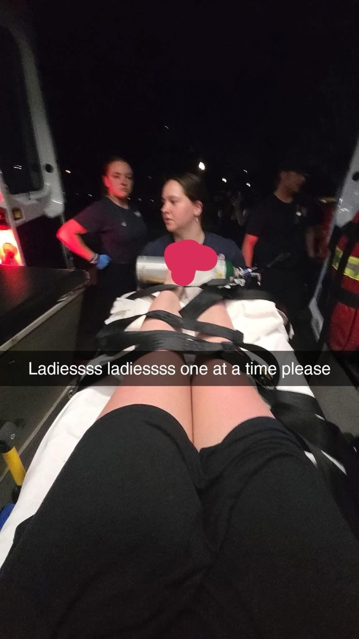 Person strapped to stretcher joking with EMTs