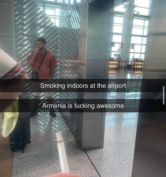 Snapchat photo of a man smoking indoors at an airport with caption “Armenia is f***ing awesome.”