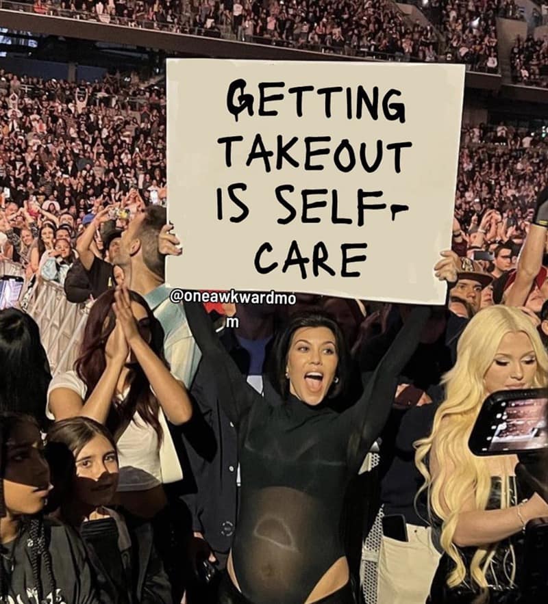 A funny motherhood meme of Kourtney Kardashian at a concert holding a sign: "Getting Takeout Is Self-Care."