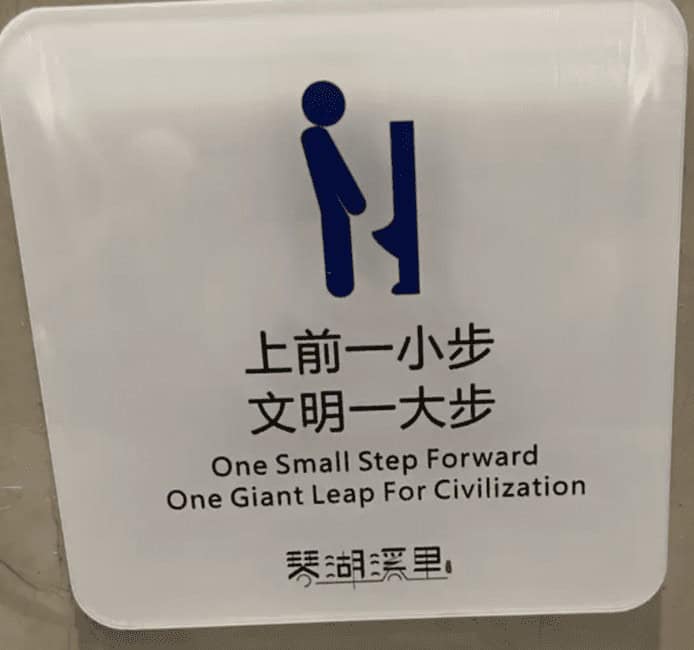 Restroom plaque: “One small step forward, one giant leap for civilization,” with icon of person stepping closer.