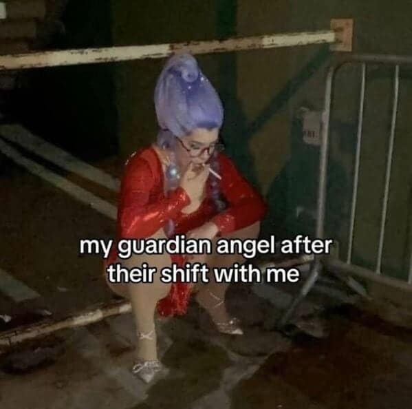 A drag performer in a red outfit and lavender beehive wig squats under a railing, smoking a cigarette with the caption: “my guardian angel after their shift with me.”