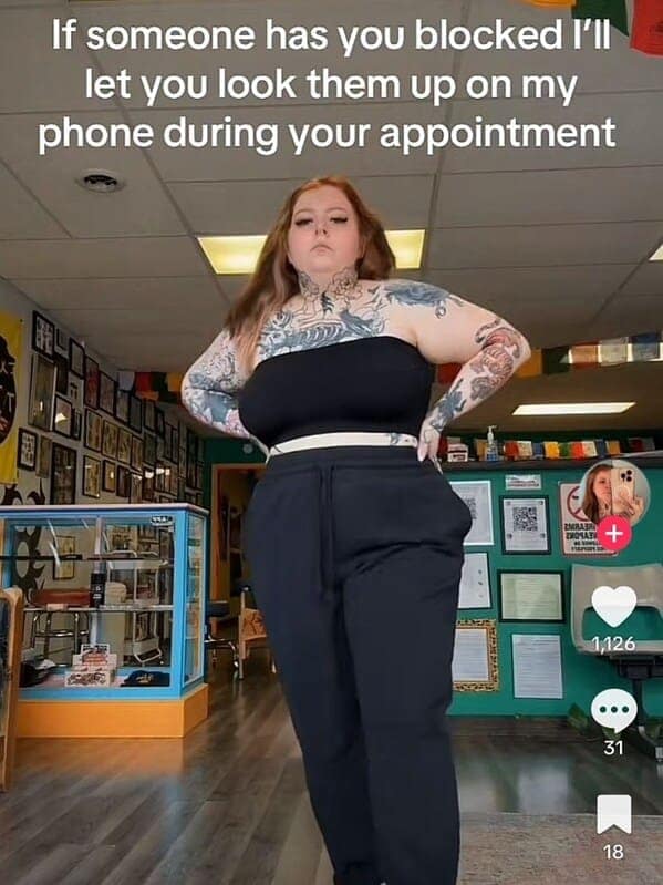 A tattooed woman in a black top and sweatpants stands confidently with the caption: “If someone has you blocked I’ll let you look them up on my phone during your appointment.”