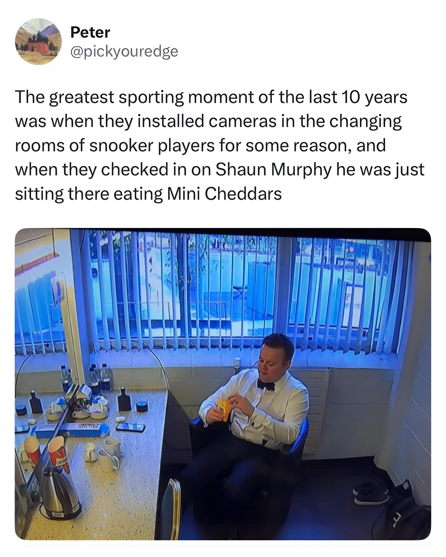 CCTV-style shot of a tuxedoed snooker player alone in a changing room, casually peeling a banana at a cluttered vanity.