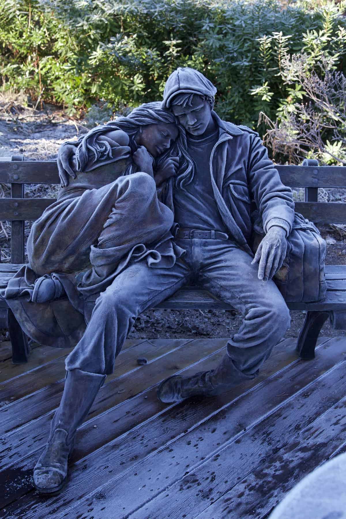 Frost-covered statue of a couple dozing together on a park bench
