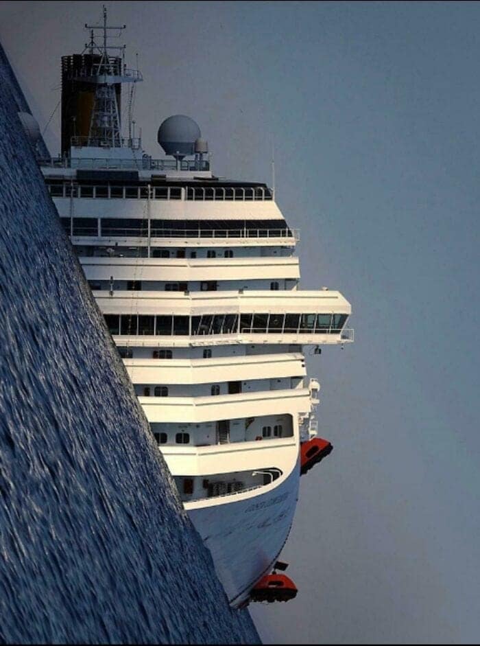 A huge cruise ship looms at a disorienting, tilted angle from behind a massive wave.