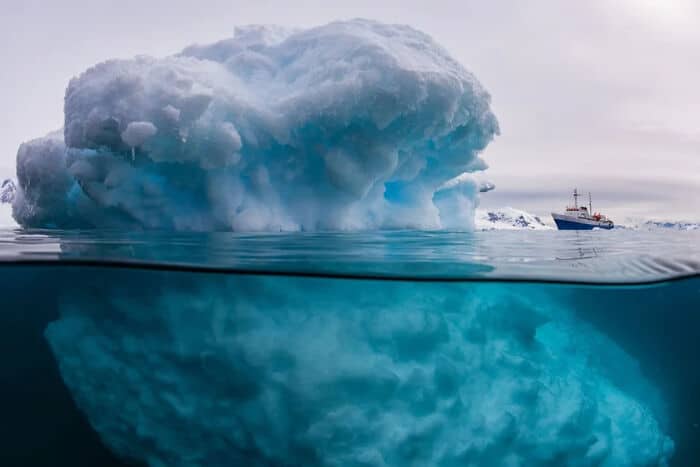 A split-level photo shows the immense, hidden underwater portion of a massive, spooky iceberg.
