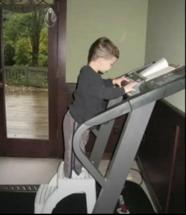 Small child standing on step stool to use a treadmill