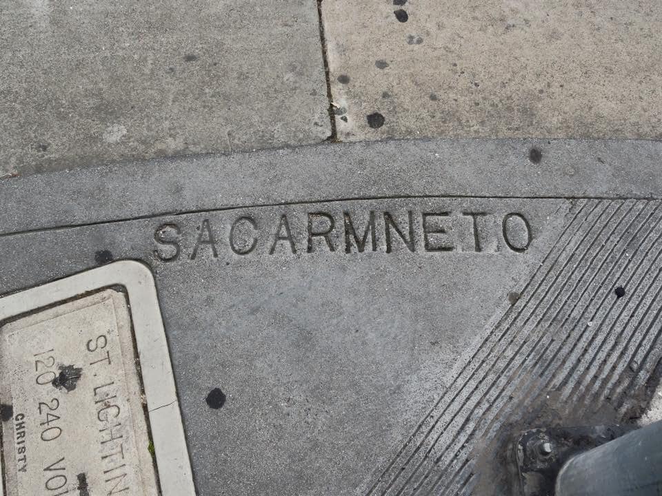 A permanent "you had one job" fail where "Sacramento" is misspelled in a concrete sidewalk.