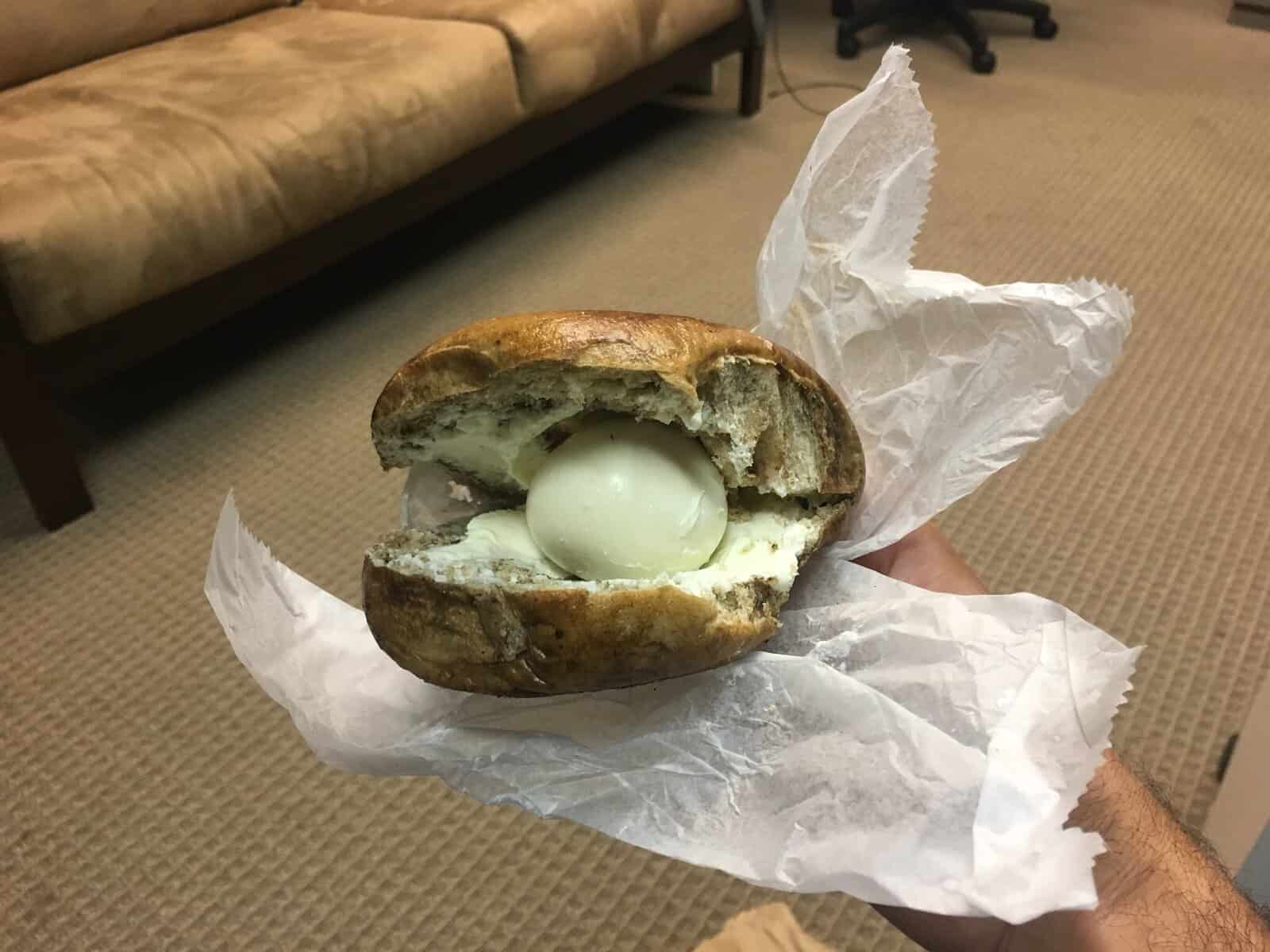 A confusing "you had one job" fail of a bagel with cream cheese and a whole, unpeeled egg.