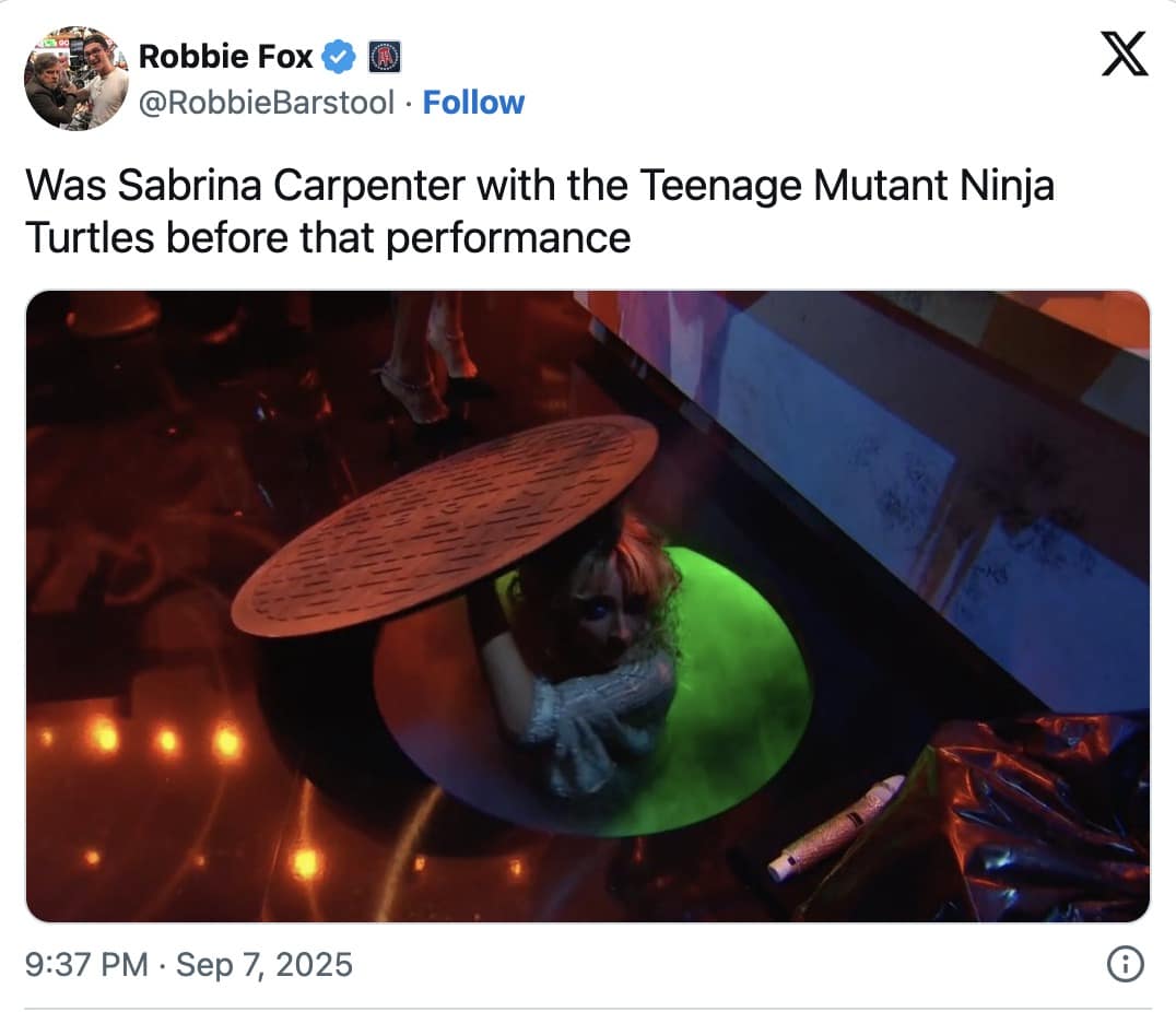 Performer emerging from a stage manhole, lifting the round cover as green light glows below