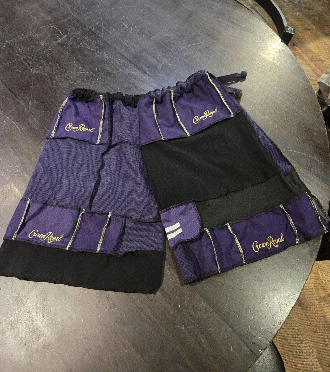 A cursed image of a pair of shorts skillfully sewn together from many purple Crown Royal bags.