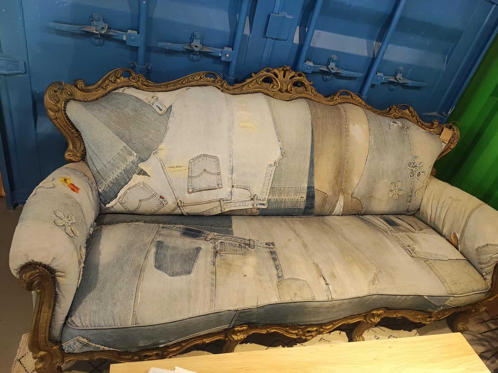 A cursed image of an ornate, vintage-style couch that has been upholstered with old blue jeans.