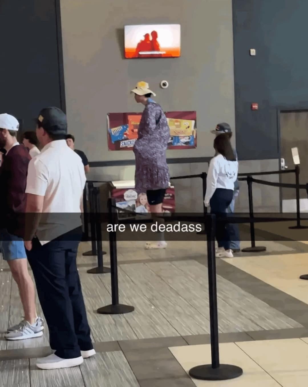 : A funny meme of two people in a trench coat attempting to sneak into a movie theater together.