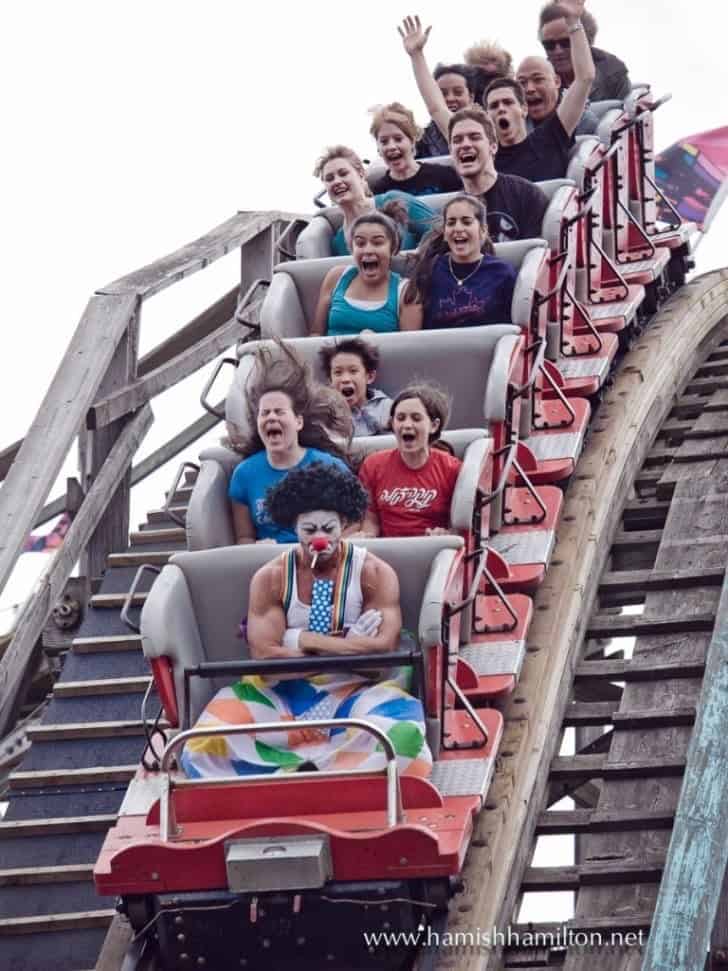 A funny rollercoaster pic of a very muscular and sad-looking clown who is not enjoying the ride at all.