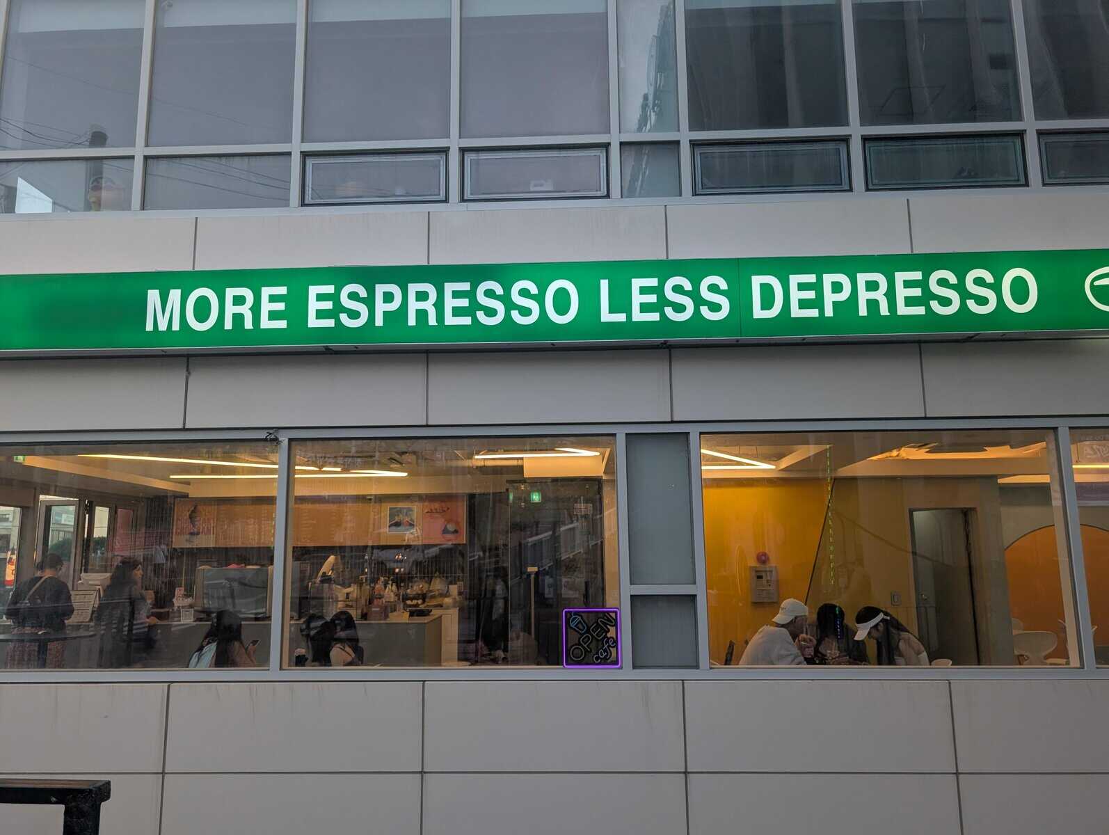 Coffee shop facade with a big green banner: “MORE ESPRESSO LESS DEPRESSO.”