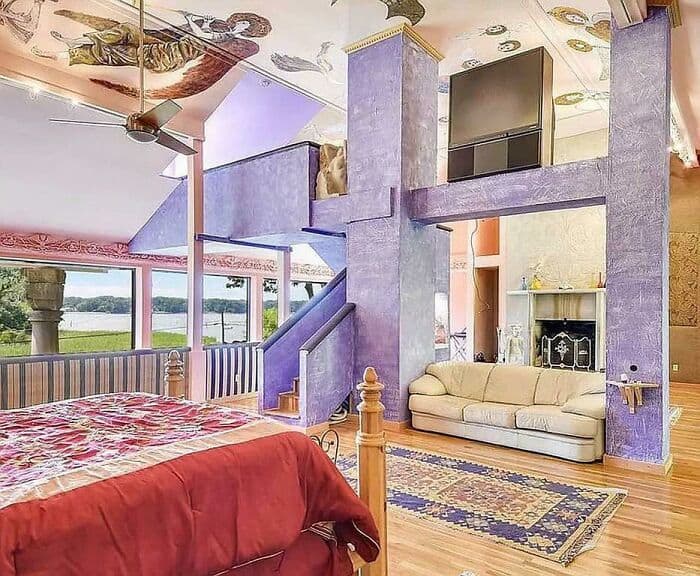 Eclectic bedroom-living space with oversized purple columns, loft nooks, and busy decor.