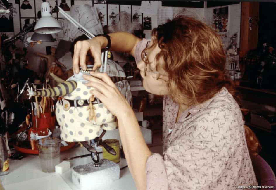 An artist in the workshop carefully adjusting the two-sided head of the Mayor of Halloween Town stop-motion puppet.