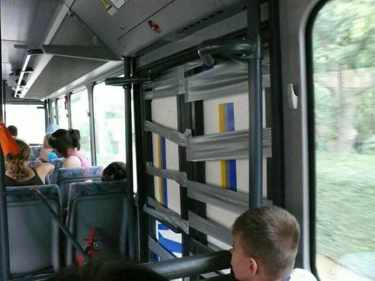 A major repair on the side panel of a public transit bus that has been done entirely and excessively with layers of silver duct tape.