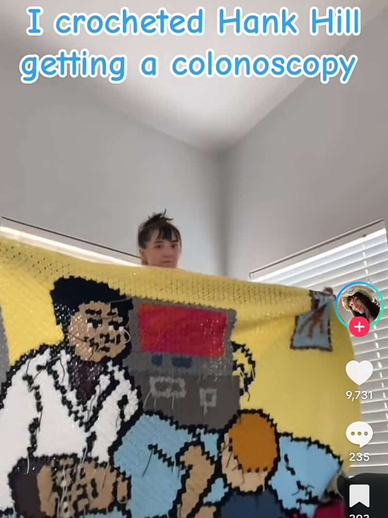 A screenshot from a TikTok video showing a creator holding up their incredible, large crocheted blanket of Hank Hill getting a colonoscopy.