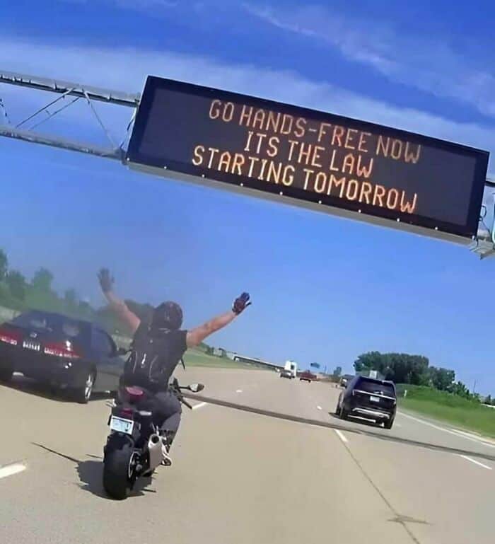 A weird photo with no context of a motorcyclist celebrating a "hands-free" law starting tomorrow.