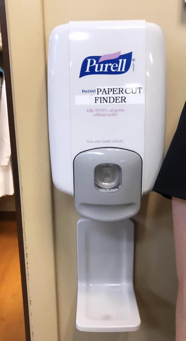 Wholesome vandalism on a Purell dispenser, relabeling it as the "Instant Papercut Finder."