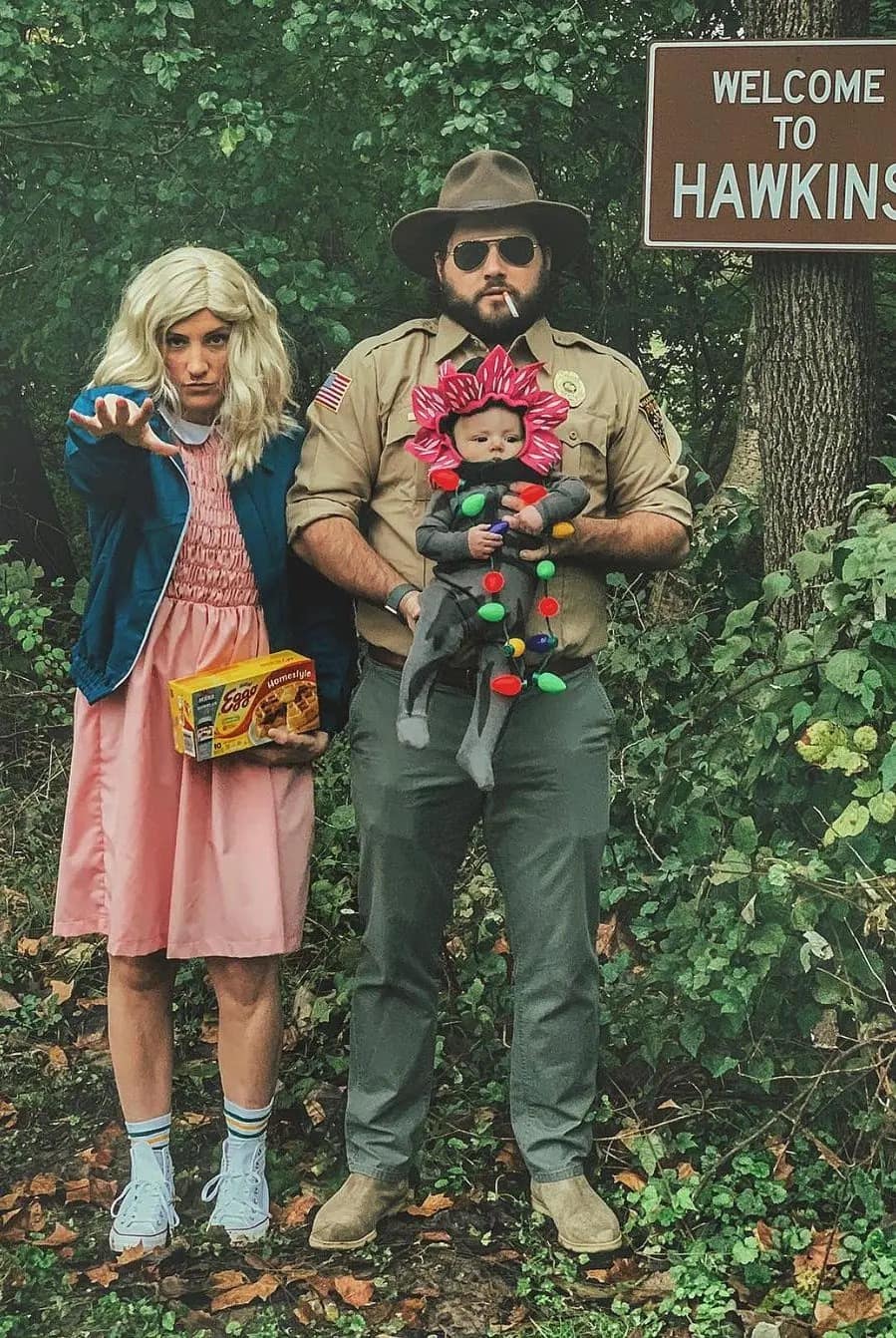 A family dressed in a Stranger Things couples halloween costume with their baby.