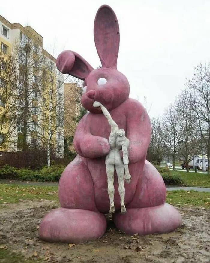 A cursed image of a giant, unsettling pink bunny statue appearing to devour a human figure.