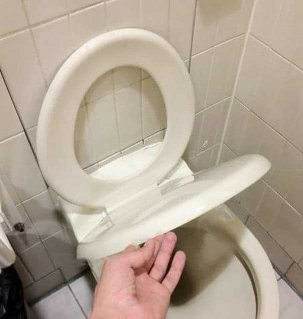 Funny fail photo showing a toilet seat installed perpendicular to the actual toilet bowl, making it useless