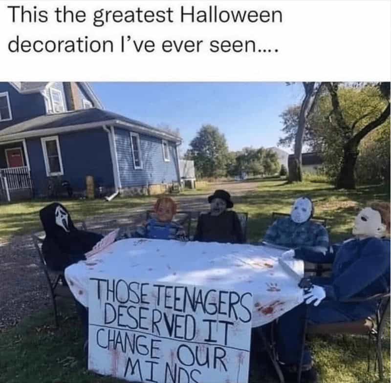 A funny yard display of horror movie villains sitting at a table with a sign defending their actions.