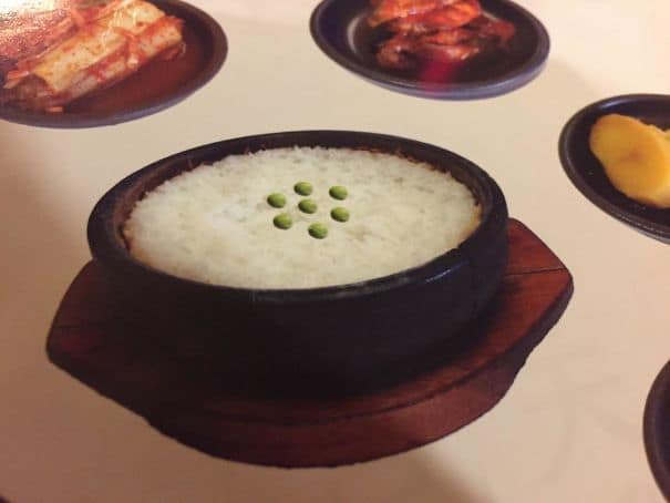 A funny photoshop fail on a restaurant menu showing a pathetic arrangement of peas poorly edited onto rice.