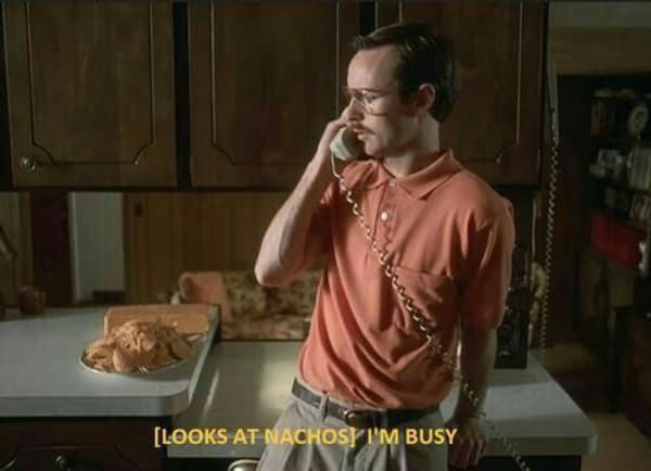 Napoleon Dynamite talking on the phone, looking at nachos, with the subtitle "[Looks at nachos] I'm busy."