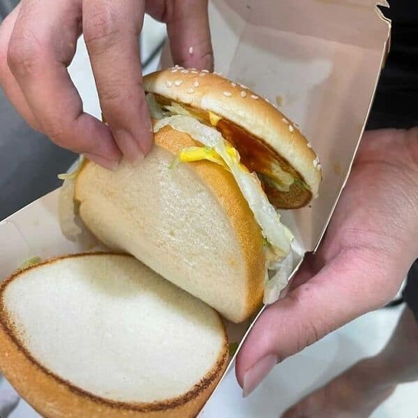 A funny picture of a McDonald's burger that was made using a single slice of white bread instead of a bottom bun.