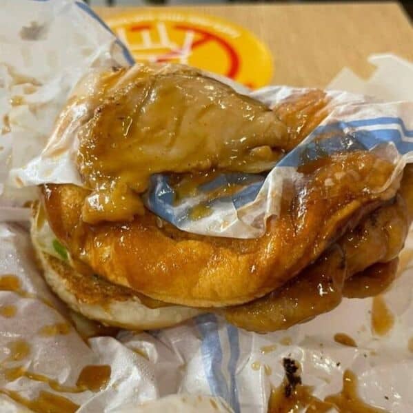 A disgusting picture of a completely mangled and sauce-soaked burger that is dissolving in its wrapper.