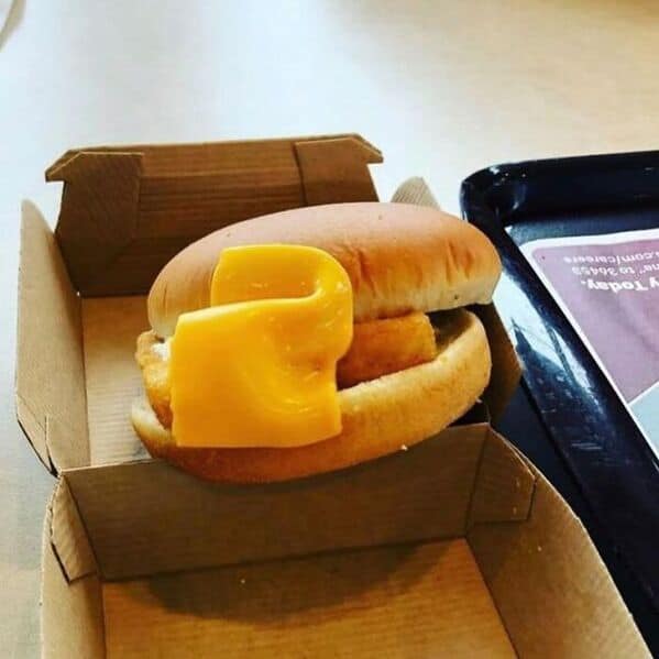 A funny picture of a poorly made sandwich where the slice of cheese was placed on top of the bun.