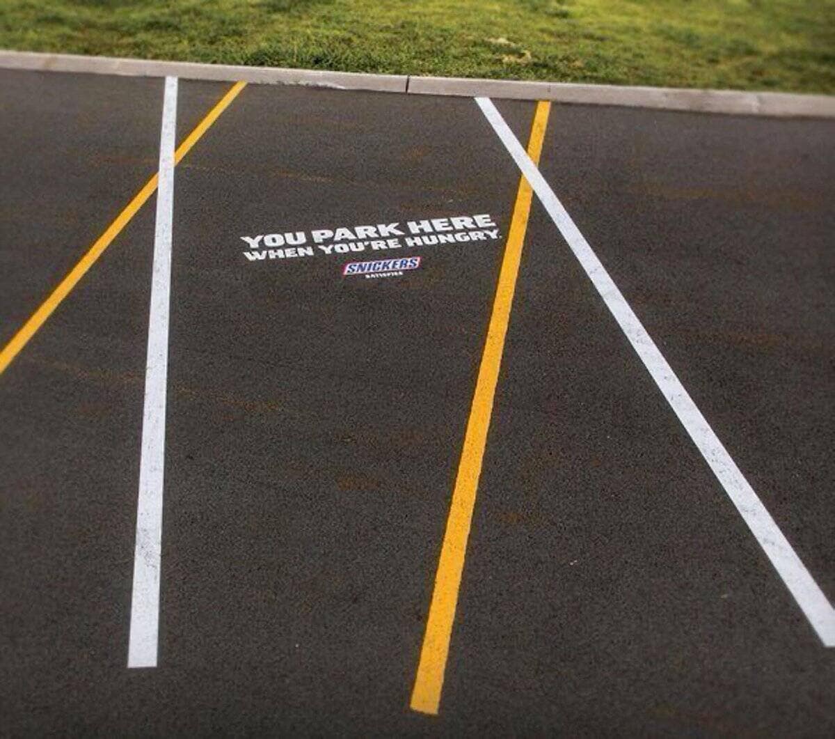 Crooked parking lines painted on asphalt for a Snickers clever ad campaign