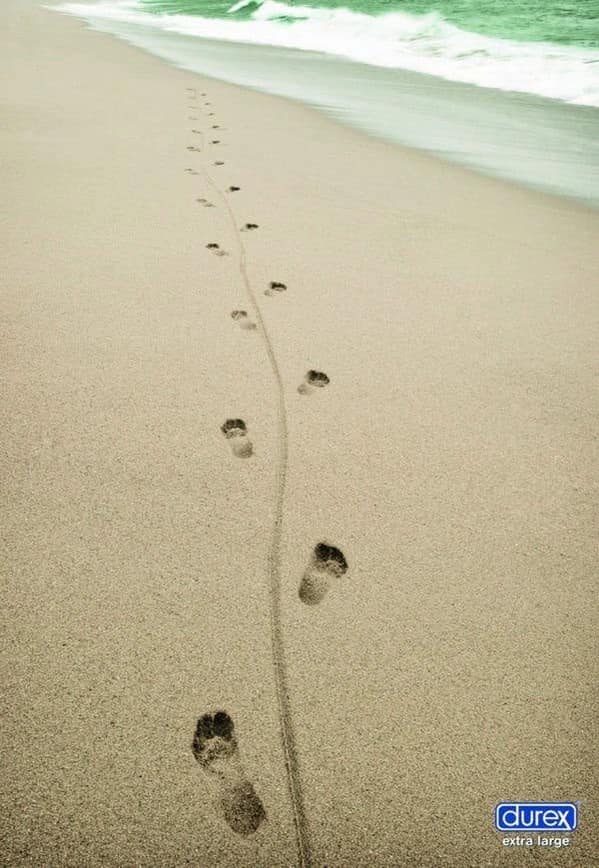 Footprints in the sand showing a dragging third leg for a Durex clever ad.