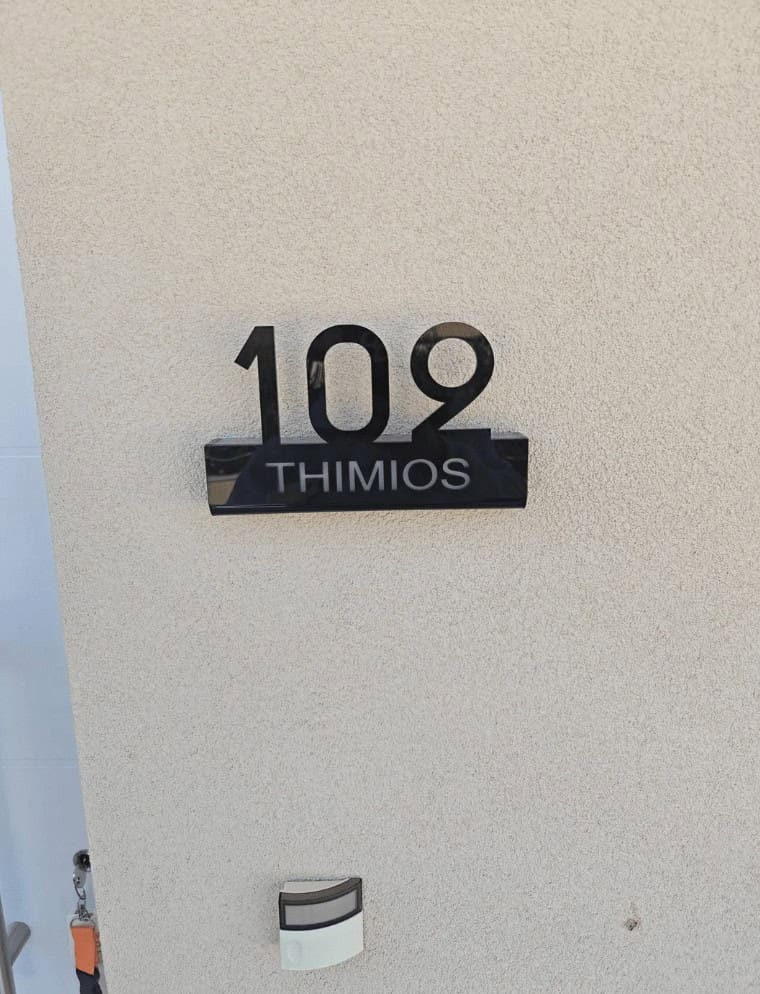 A funny design fail on a house number sign where the "109" is much larger than the name "THIMIOS."