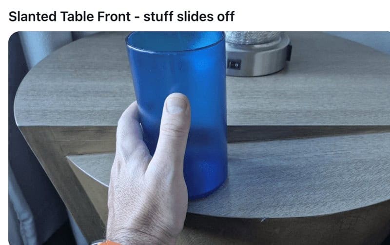 A funny design fail of a bedside table with a slanted, curved front, causing a cup to slide right off.