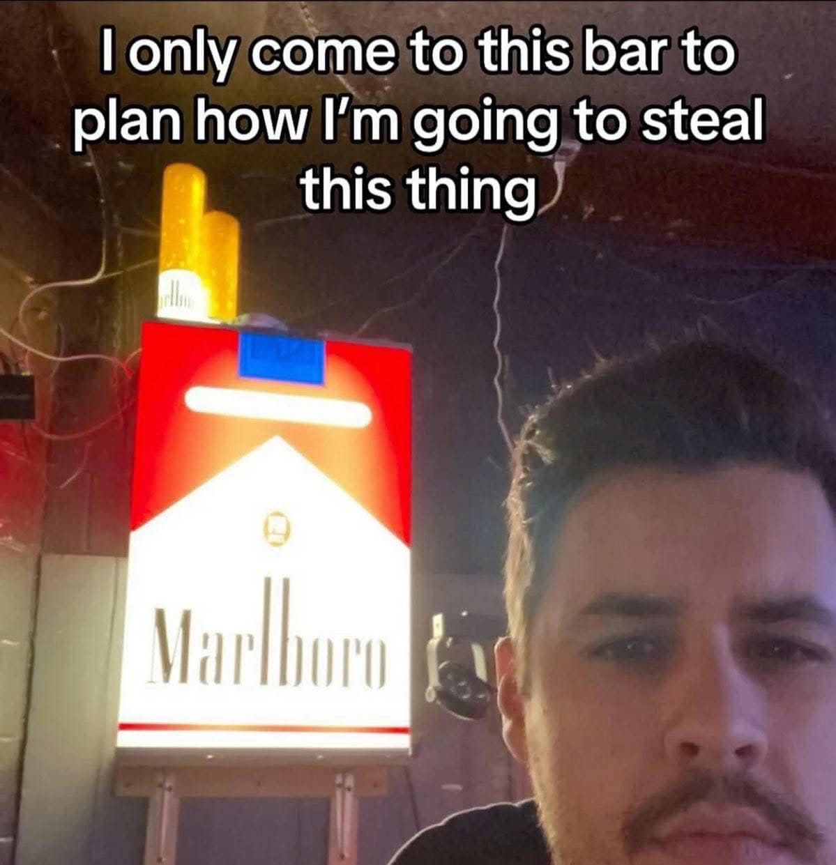 A funny pic of a man at a bar, captioned "I only come to this bar to plan how I'm going to steal this thing."